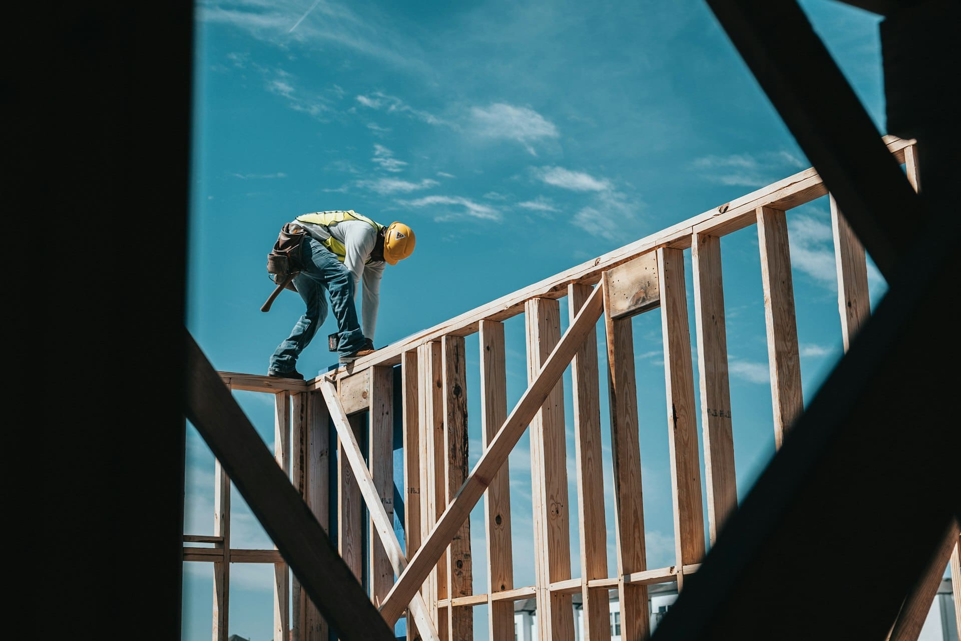 Builder in hard hat working on a timber house frame