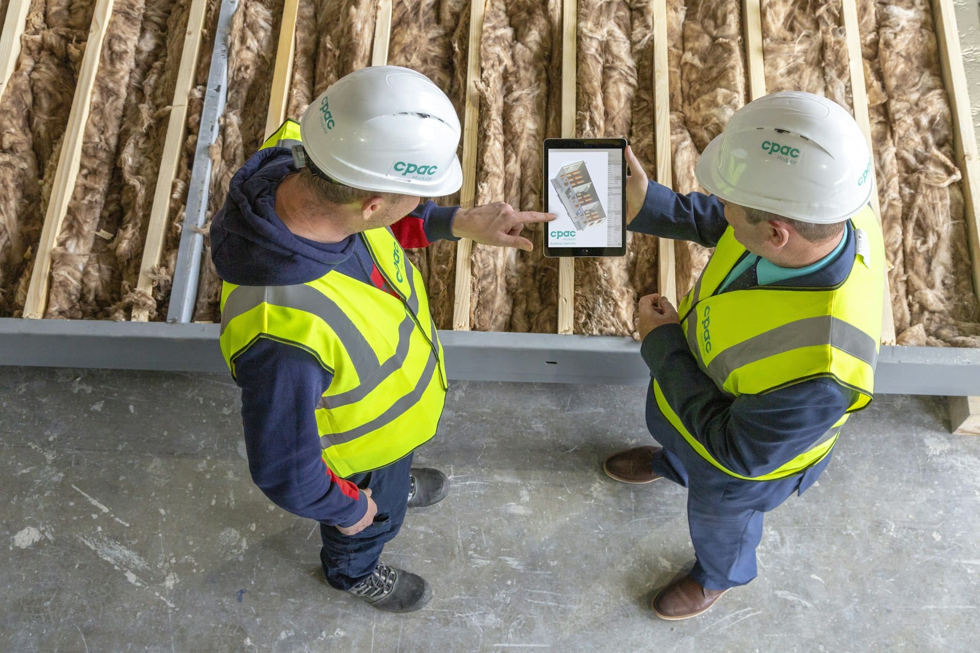 Two construction workers reviewing plans on a tablet